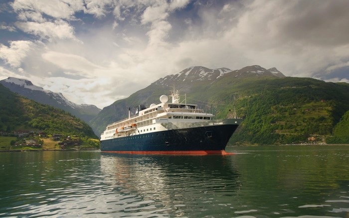 Cruise ship sailing in a Norwegian fjord with mountains