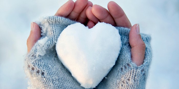 Hands holding a heart-shaped snowball