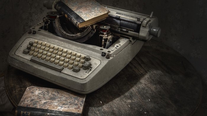 Old typewriter with a book on a wooden table