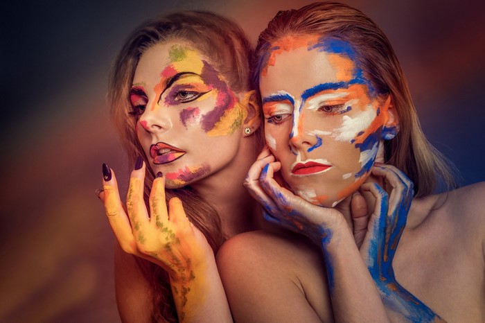 Two women with colorful body paint posing