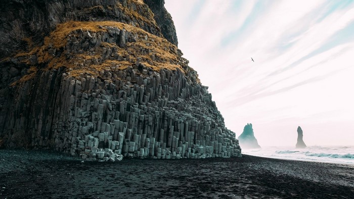 Basalt columns on black sand beach with sea stacks