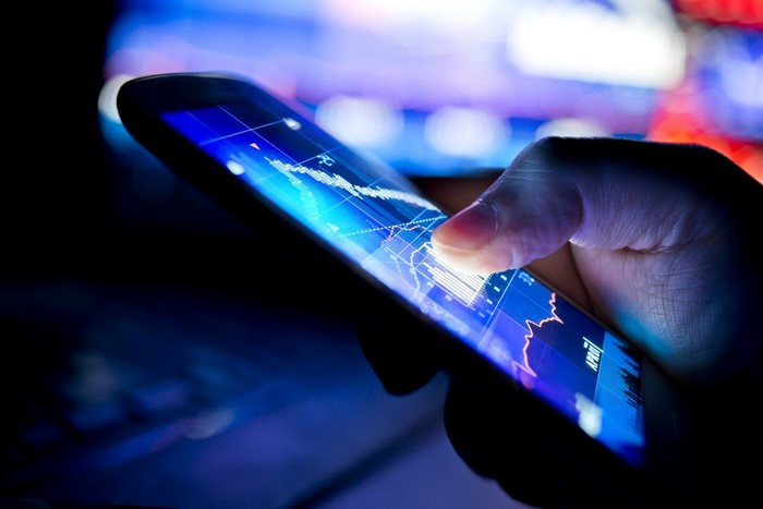 Hand holding smartphone displaying stock market graph