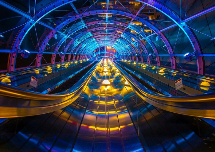 Escalator tunnel with colorful lights at night