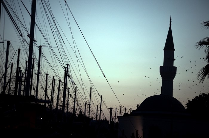 Mosque minaret and boats masts at dusk