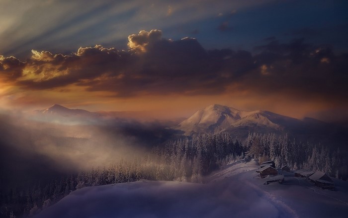 Snowy mountain landscape with cabins at sunset