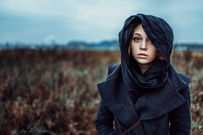 Woman in dark headscarf and coat in field