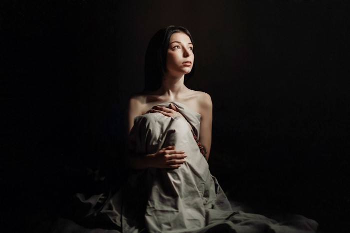 Woman wrapped in a sheet in darkness