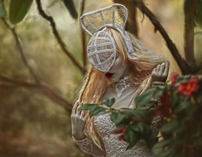 Woman in elaborate costume and mask in a forest