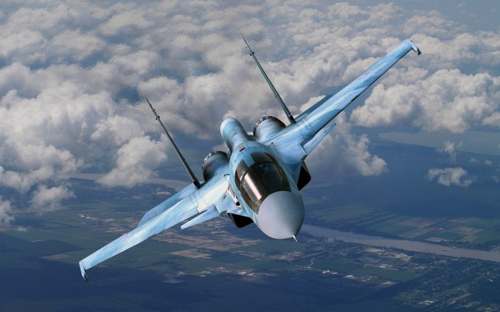 Sukhoi Su-34 fighter jet flying over clouds and land