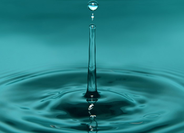 Water drop falling into blue water
