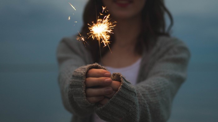 Woman holding a sparkler at dusk
