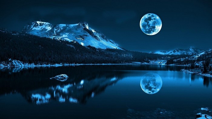 Full moon over a lake and mountains at night
