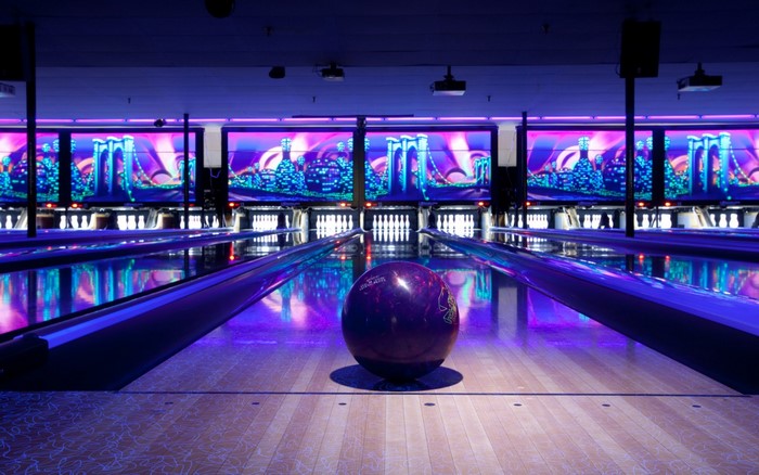 Bowling alley with purple and blue lights and cityscape graphics