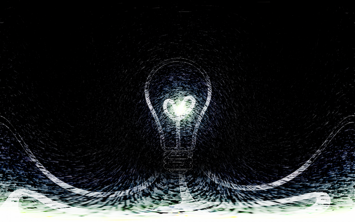 Light bulb with heart filament in darkness