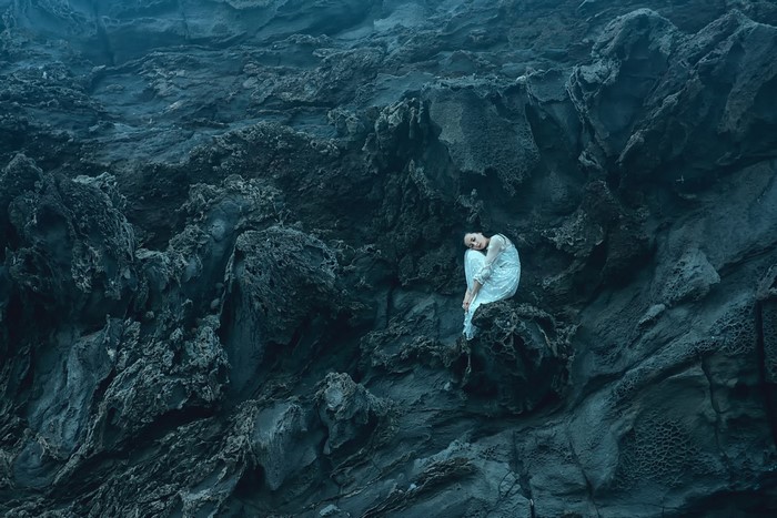 Woman in white dress sitting on rocks