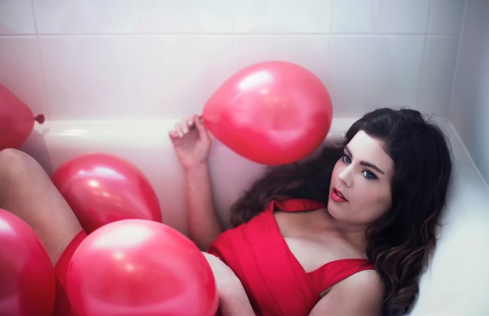 Woman in bathtub with red balloons