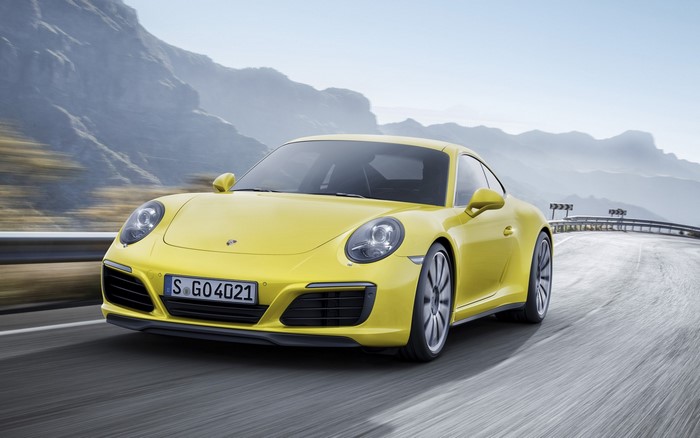 Yellow Porsche 911 Carrera driving on a mountain road