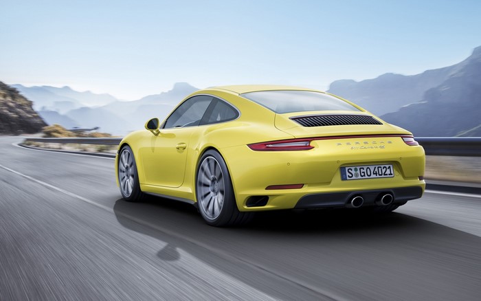 Yellow Porsche 911 Carrera 4S driving on a mountain road