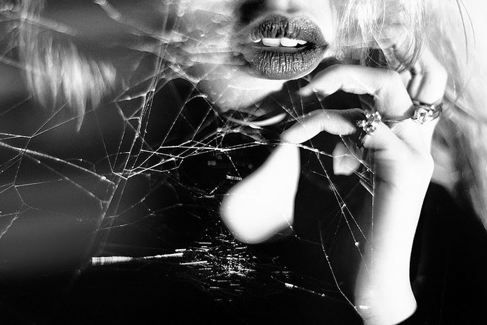 Monochrome close-up of woman's lips and hand with rings