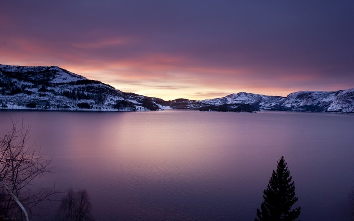 Snowy mountains reflecting in a lake at sunset
