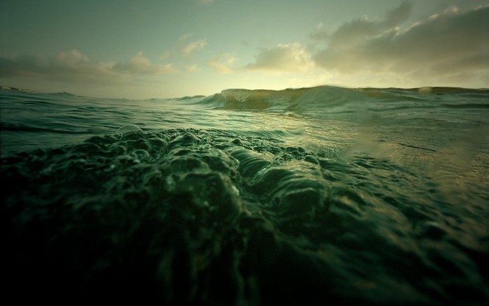 Ocean waves at sunset with clouds