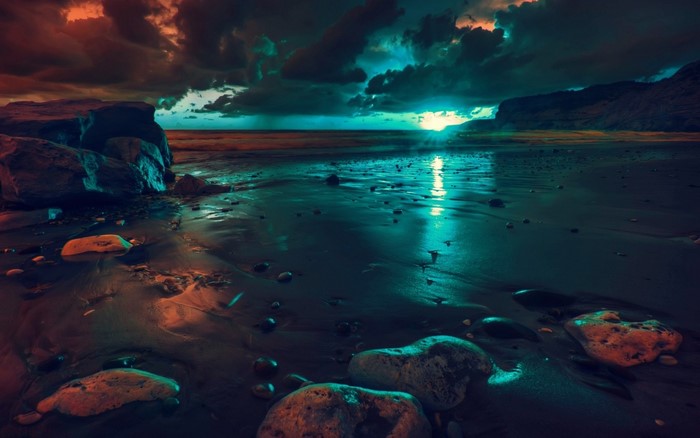 Beach with rocks and ocean reflection at sunset