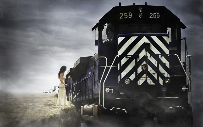 Woman in white dress standing next to a train