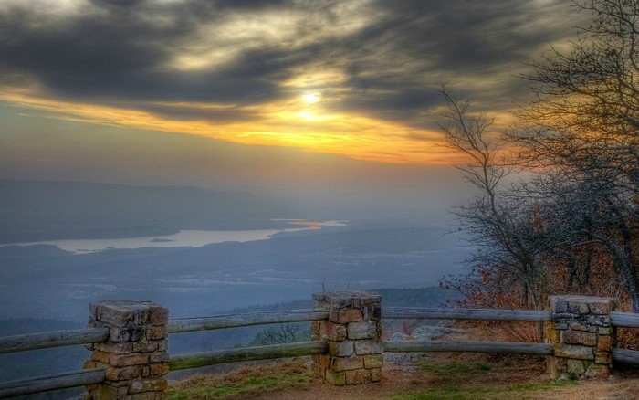 Sunset over a misty landscape with a wooden fence