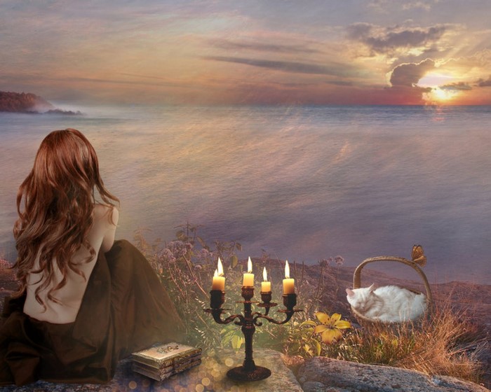 Woman watching sunset over the sea with a cat in a basket