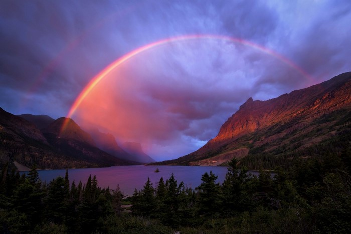 Rainbow over a lake and mountains at dusk