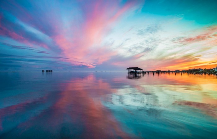 Sunset over the ocean with reflections and a pier