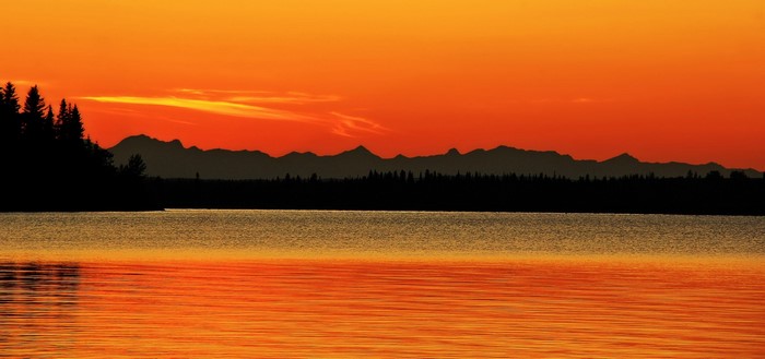 Sunset over a lake with mountains and trees