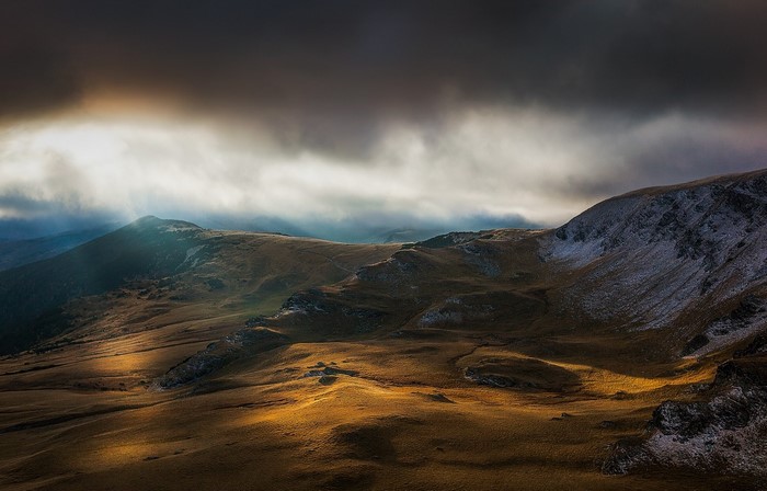 Sunlight breaking through clouds over mountainous terrain