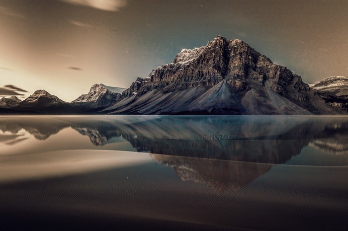Snow-capped mountains reflected in a calm lake at dawn