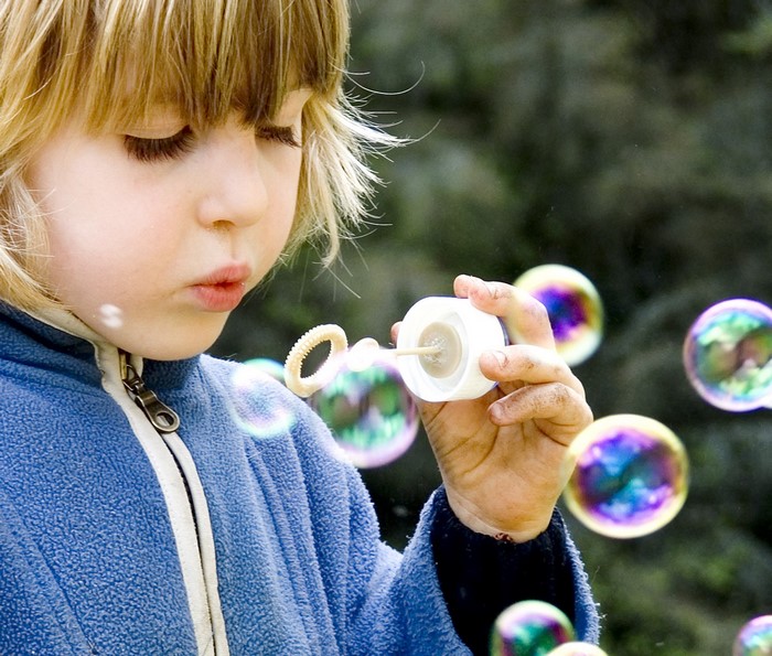 Child blowing bubbles outdoors