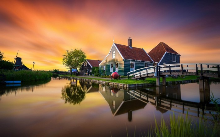 Dutch village with windmill and canal at sunset