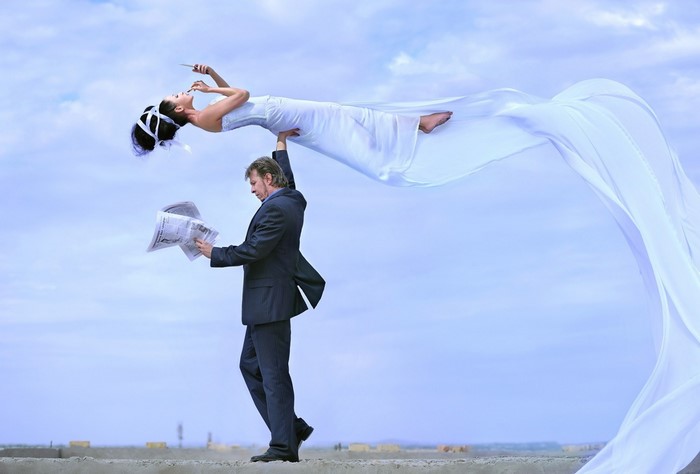 Man holding woman in white dress with flowing fabric