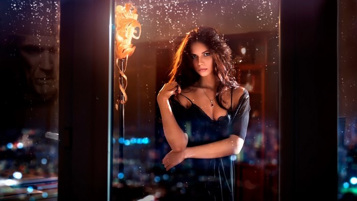 Woman in a black dress posing by a window