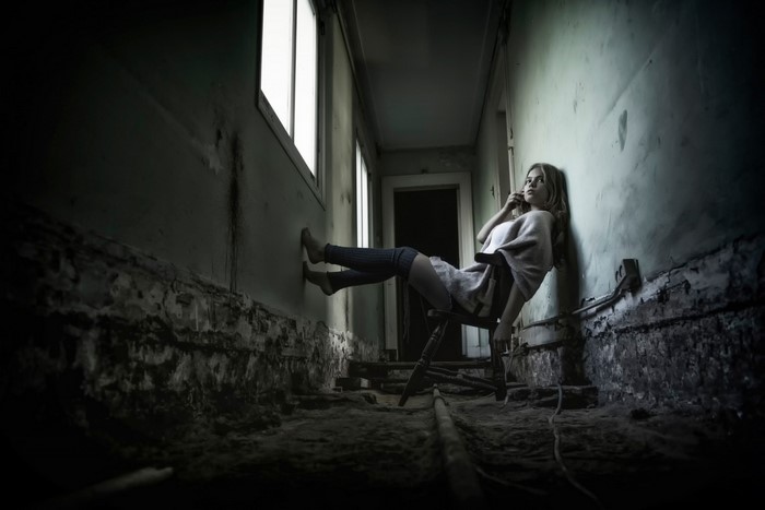 Woman sitting in a chair in a dark hallway