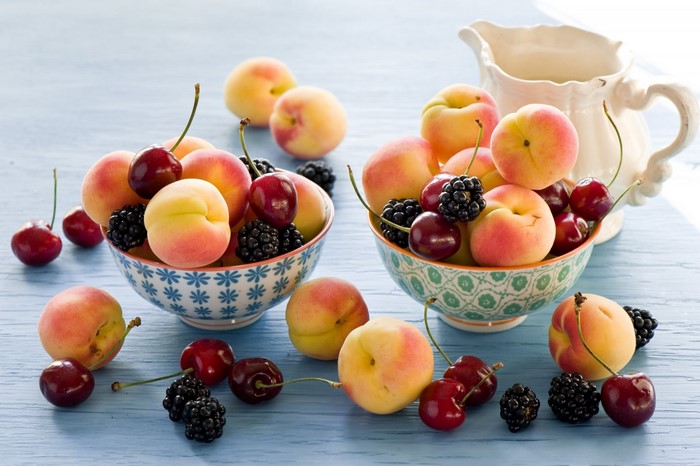 Still life of peaches, cherries, and blackberries in bowls