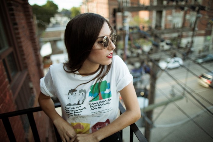 Woman wearing sunglasses and a graphic t-shirt on a balcony