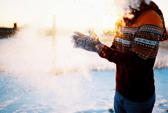 Person throwing snow in winter sunlight