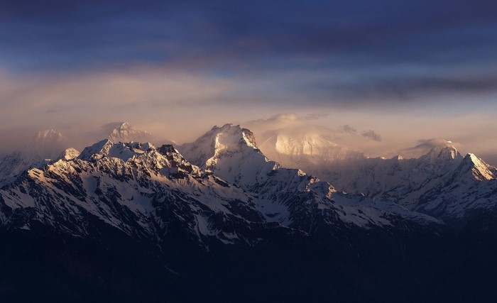 Snowy mountain range at sunrise with clouds