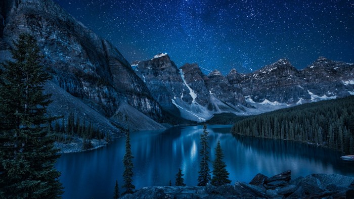 Moraine Lake at night with stars and mountains