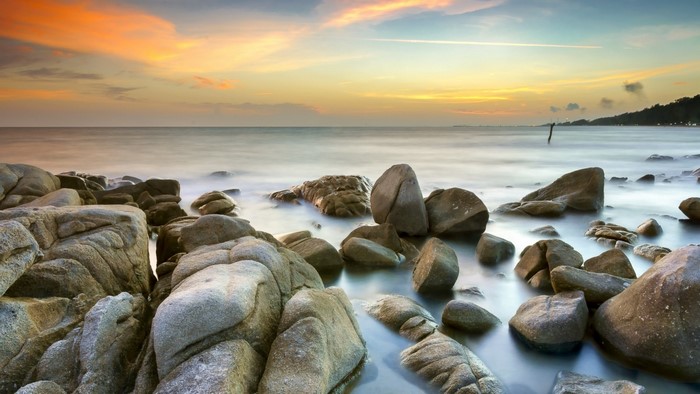 Rocky shore at sunset with calm ocean waves