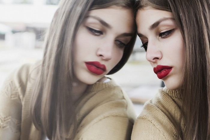 Woman with red lipstick looking in mirror