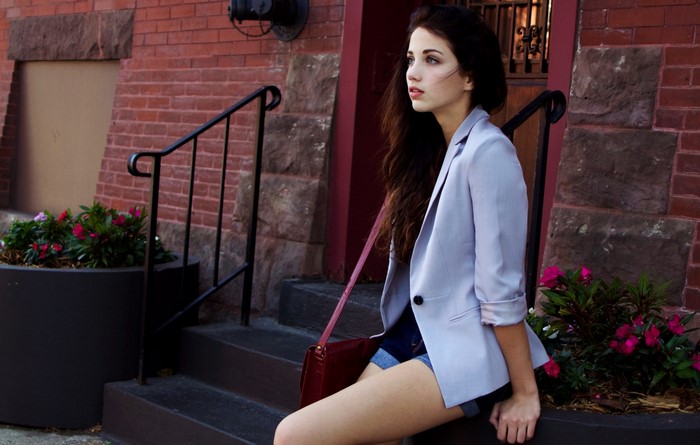 Emily Rudd wearing a light blue blazer and denim shorts outdoors