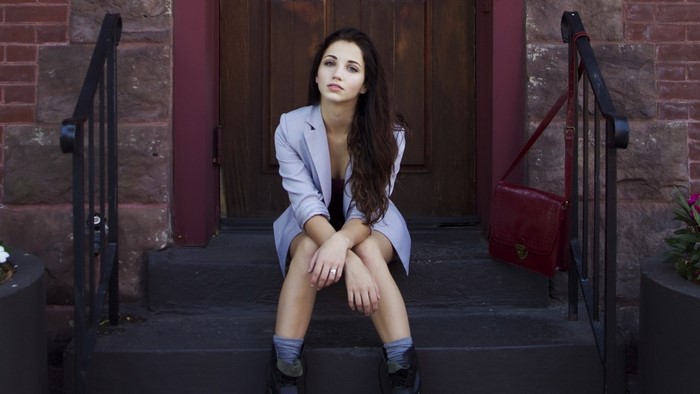 Woman with long brown hair wearing a blazer sitting on steps