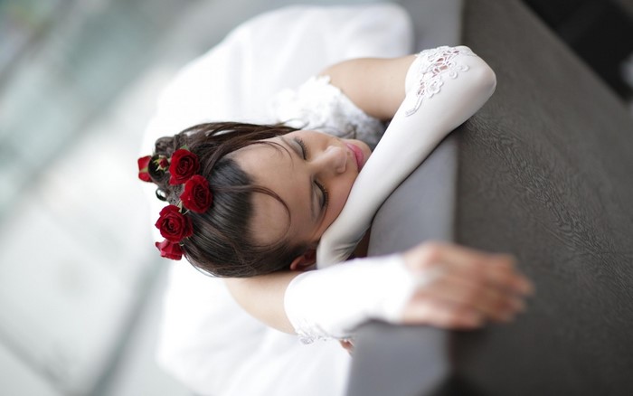 Bride with red roses in hair resting head on arm
