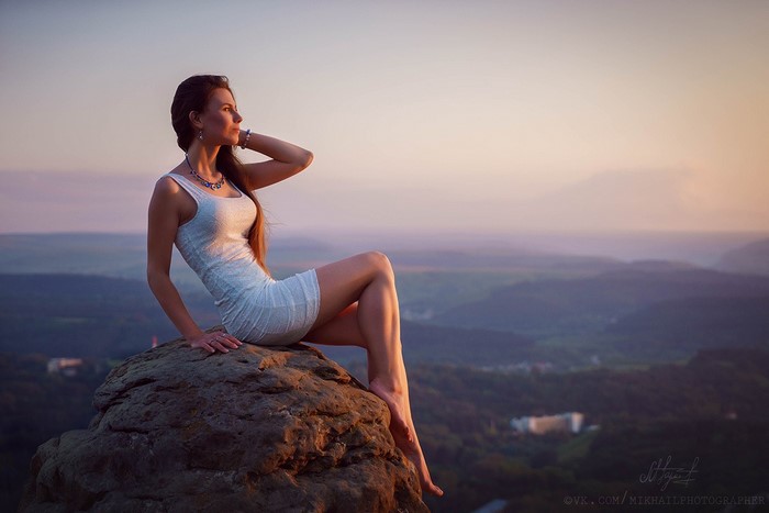 Woman Sitting on Rock at Sunset Over Looking Valley